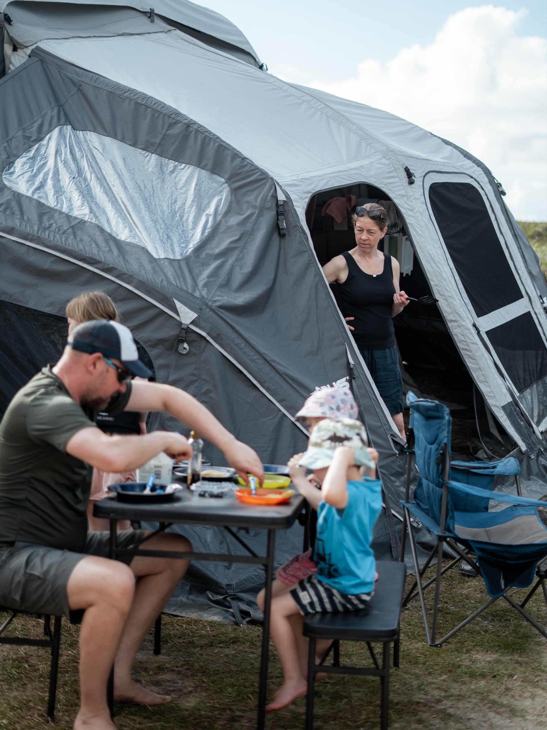 An OPUS family having dinner beside their camper