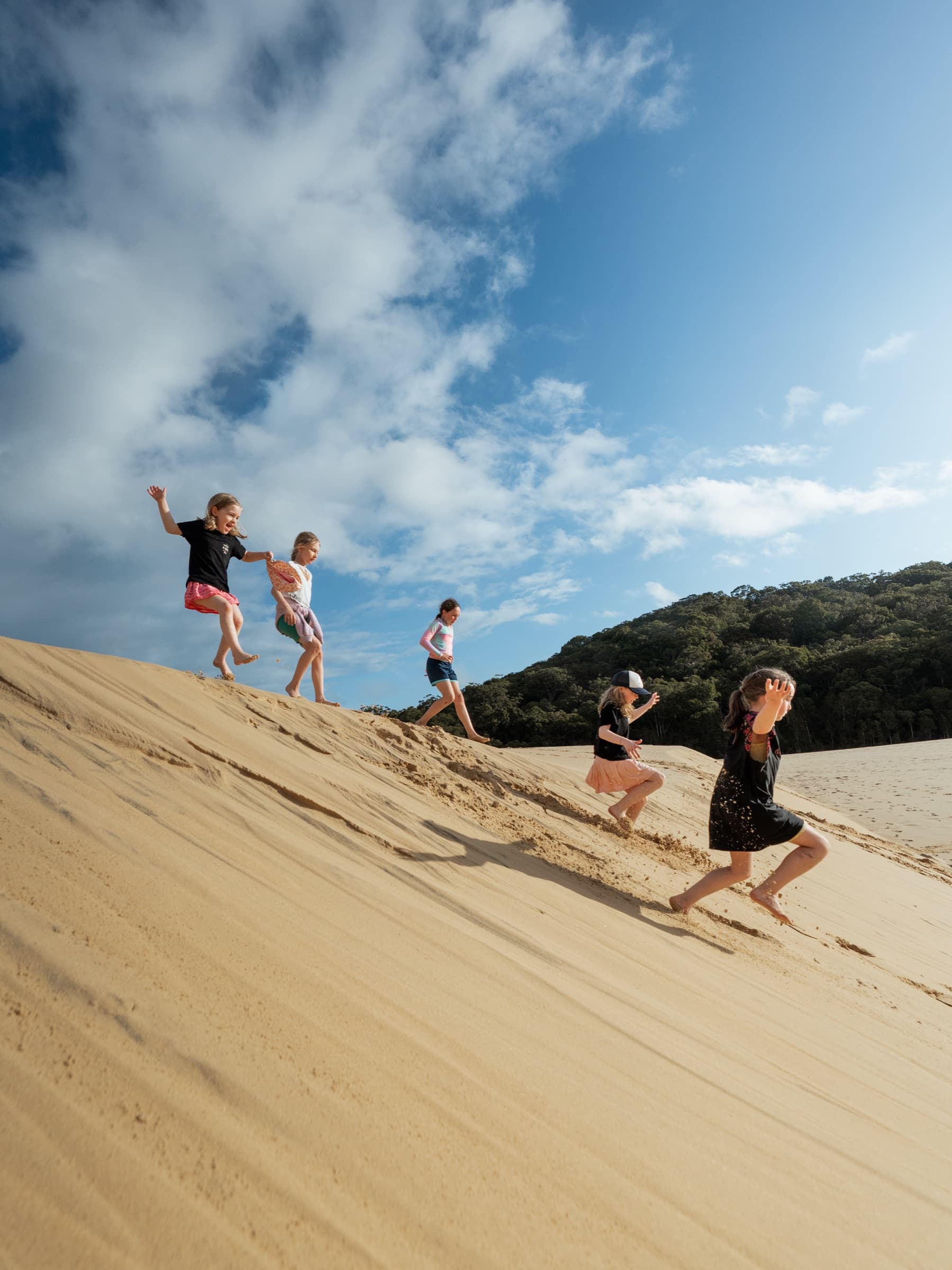 Kids running down a sand dune