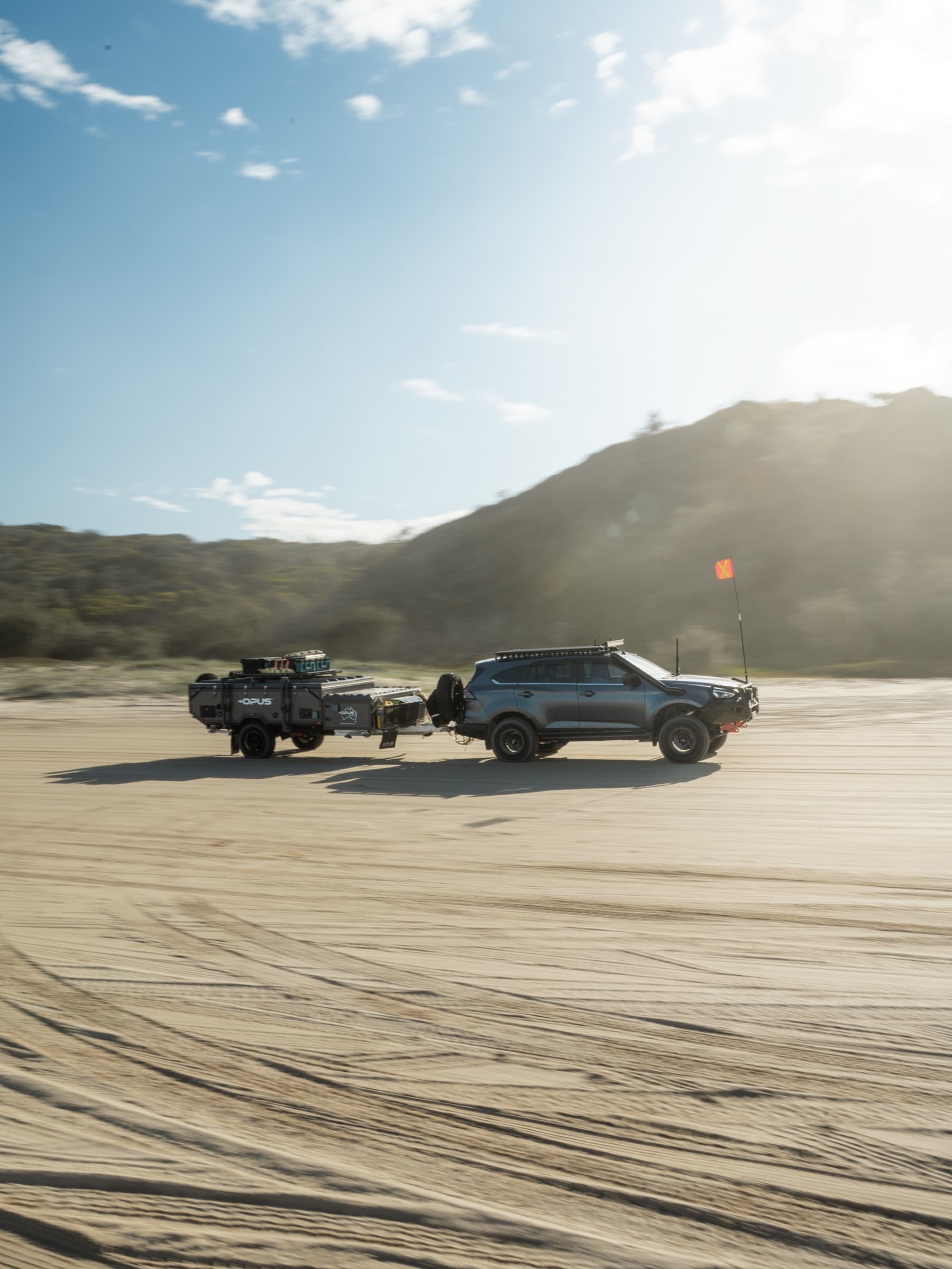 4WD towing an OPUS camper trailer along the beach