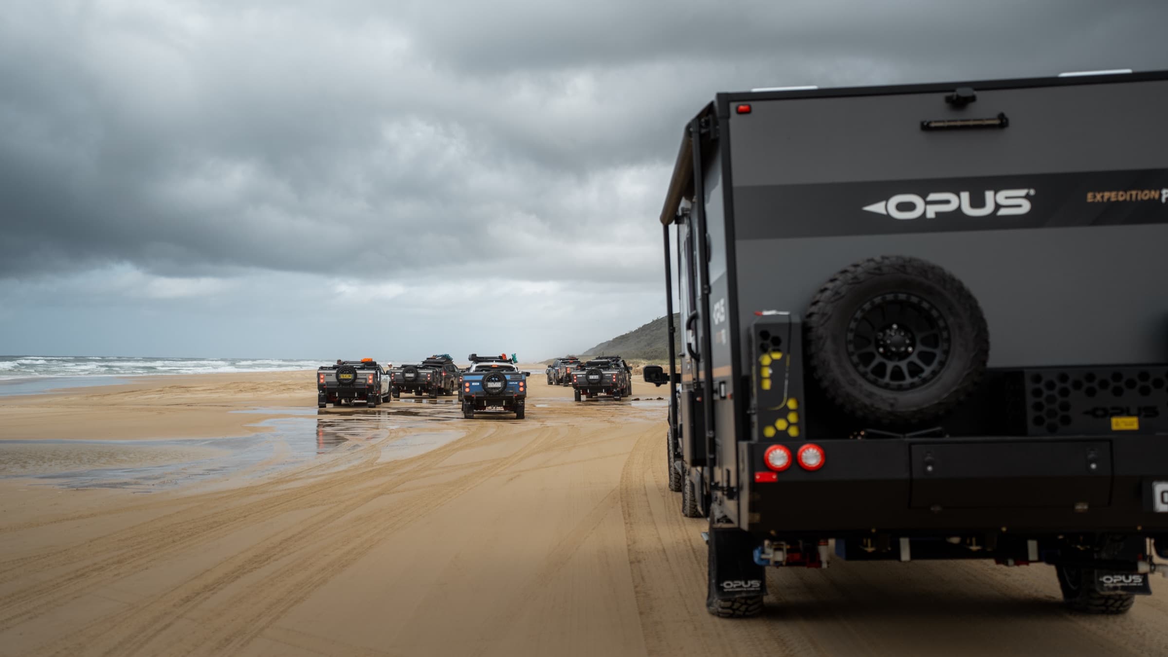 Convoy stretching down the beach behind an OPUS hybrid