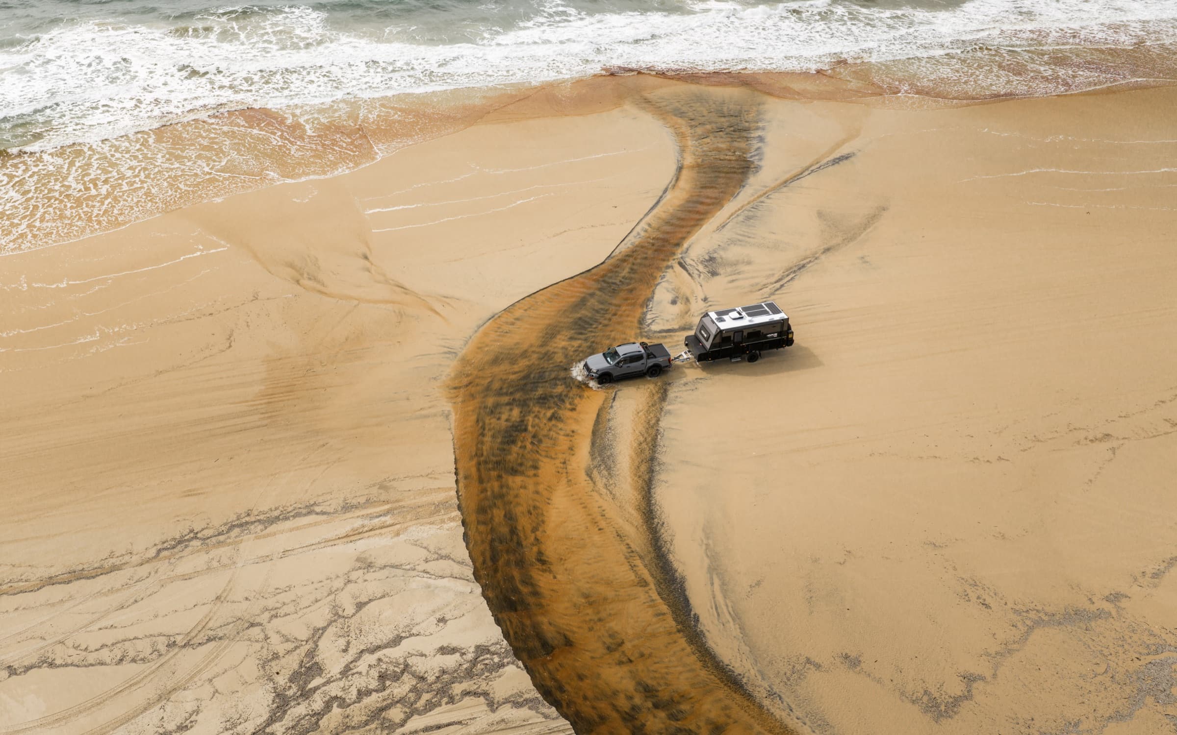 Two rigs crossing a tidal creek on the sand