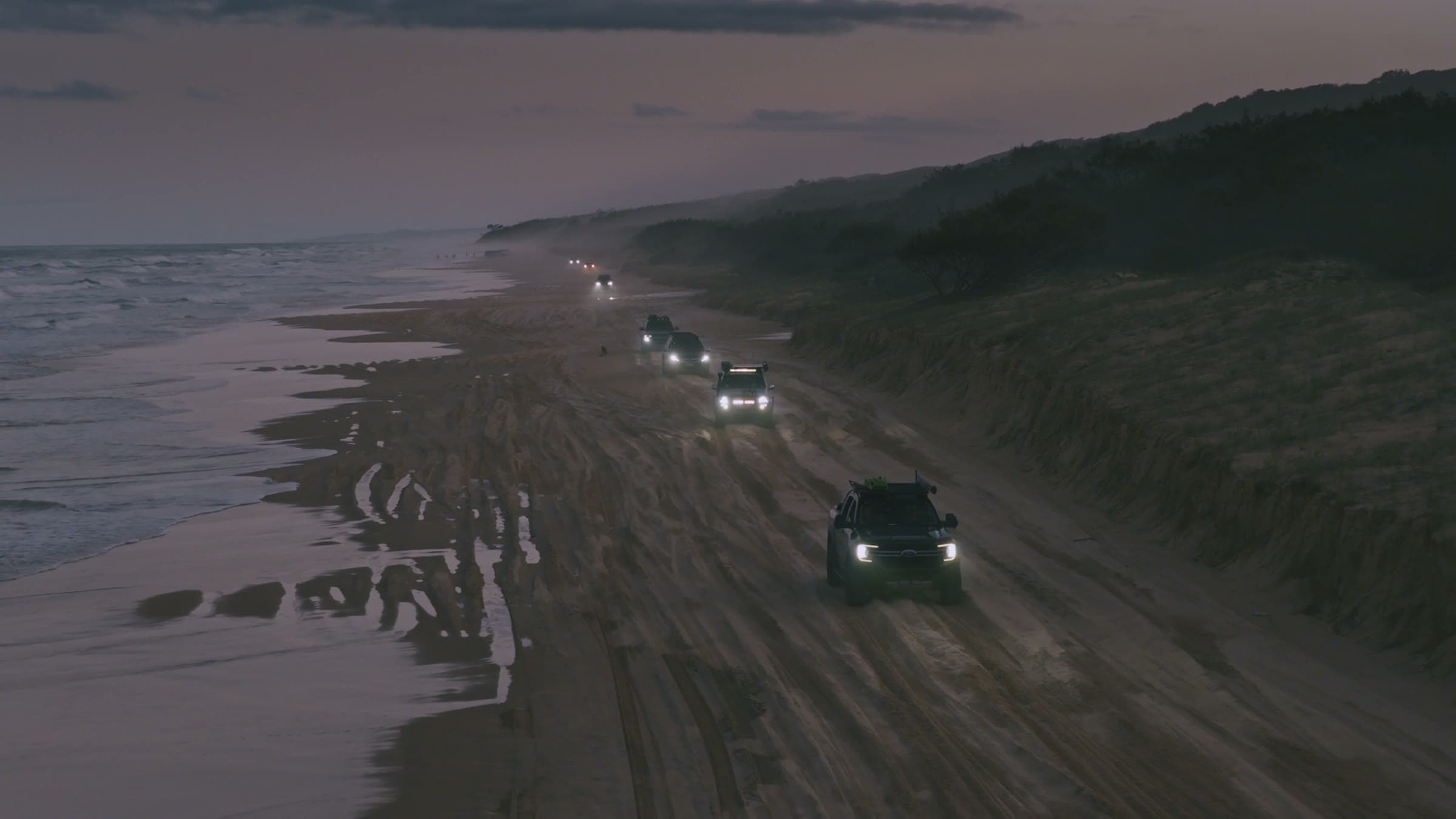 OPUS convoy driving K'Gari's beach at dusk
